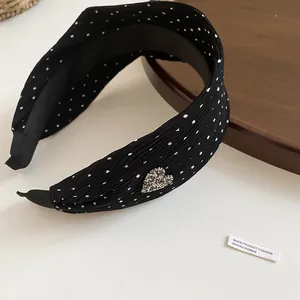 Detail view of black polka dot headband with pleated fabric and a rhinestone heart
