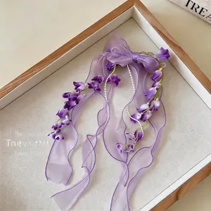 Primo piano della clip per capelli a fiocco in chiffon viola con eleganti nastri di fiori e perle