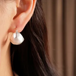 Minimalist brushed silver geometric semi-circle hoop earrings worn on a model ear