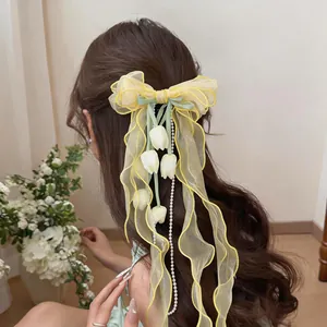 Dettaglio della clip per capelli a fiocco giallo in chiffon con tulipani e perle