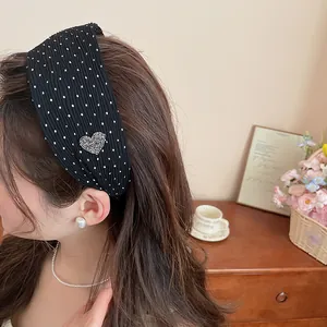 Detailed view of a black wide pleated headband featuring white polka dots and a rhinestone heart