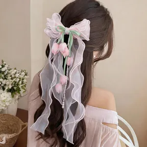 Dettaglio di fermaglio a fiocco in chiffon rosa con nappe di tulipani e perle su capelli