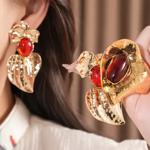 Detailed view of oversized gold hammered earrings with red oval resin centers