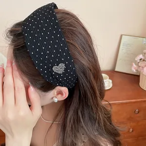 Close-up detail of a black polka dot headband featuring a sparkling rhinestone heart charm