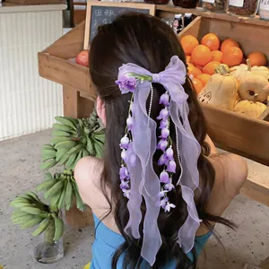 Dettaglio di un fermaglio per capelli in chiffon viola con fiori di mughetto fata.