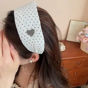 Close-up of a stylish polka dot headband with a sparkling rhinestone heart on a model.