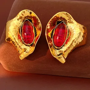 Detailed macro shot of vintage hammered gold earrings featuring red oval resin stones in detail