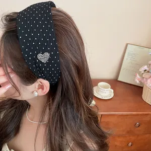Close-up of black polka dot headband with a sparkling rhinestone heart on an Asian model.