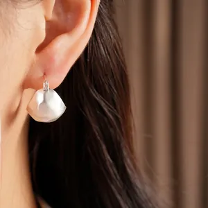 Detailed close-up view of a minimalist brushed silver geometric earring worn on ear