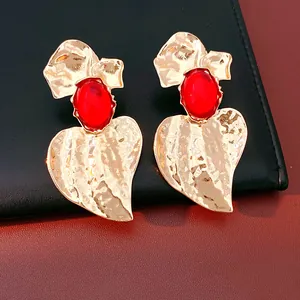 Detailed view of vintage gold hammered leaf earrings featuring vibrant oval red resin stones