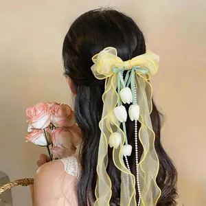 Dettaglio di un fermaglio per capelli a fiocco in chiffon giallo con tulipani e perle