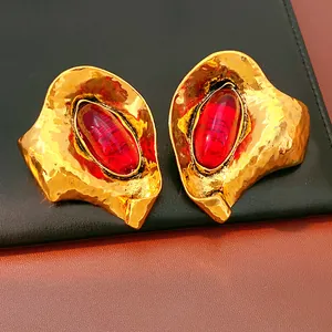 Detailed shot of vintage geometric gold earrings with red oval resin stones.