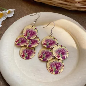Dettaglio di orecchini in stile cinese con stampa di orchidea viola su dischi dorati
