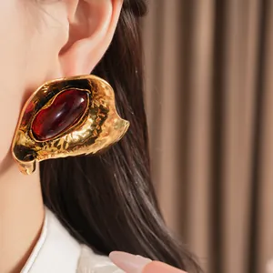Close-up detail of vintage gold-tone hammered earrings with red oval resin center