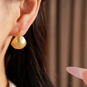 Detail view of elegant brushed gold geometric semi-circular earrings worn by model