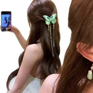 Élégante pince à cheveux papillon tricotée verte avec glands en perles sur un modèle