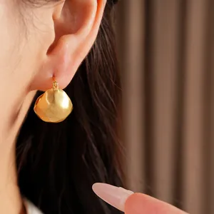 Detailed view of brushed gold geometric semi-circle hoop earring on model's ear