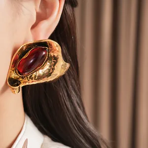 Macro detail of geometric ruby red resin earring with hammered gold-tone metal finish