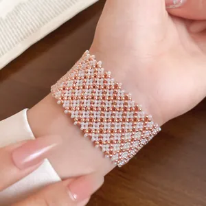 Nahaufnahme eines eleganten, geflochtenen Armbands aus rotgoldenen und weißen Perlen