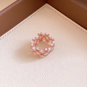 Nahaufnahme eines roségoldenen und weißen geflochtenen Perlenrings mit eleganter Textur