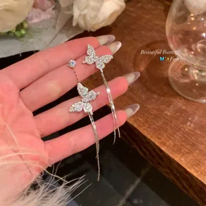 Detailed close-up of sparkling asymmetric butterfly tassel earrings on a wooden background