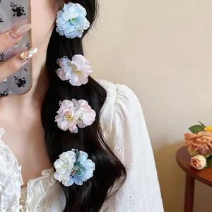 Detail of sweet fabric flower hair clips in pastel blue and pink on long dark hair