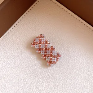 Nahaufnahme eines roségoldenen und weißen geflochtenen Perlen-Magnetarmbands