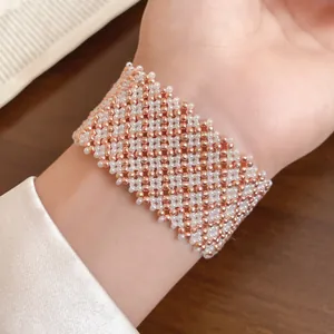 Detailansicht eines handgewebten Magnetarmbands mit roségoldenen und weißen Perlen