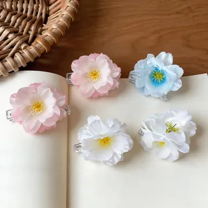 Detail view of five colorful fabric flower hair clips on a light cream surface.