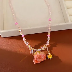 Elegant handmade glass beaded necklace with a preserved pink rose and iridescent charm