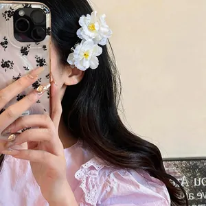 Detailed shot of an elegant white fabric flower hair clip being worn in long dark hair.