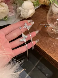 Detailed view of asymmetric butterfly tassel earrings with sparkling crystals