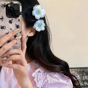 Elegant white and blue fabric flower hair clips worn by a model in a lifestyle setting