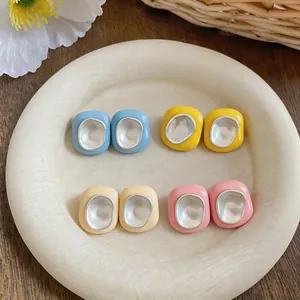 Détail de boucles d'oreilles en émail de style coréen déclinées en quatre teintes douces.