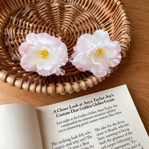 Detail view of sweet pink and white fabric flower hair claw clip on a wicker basket.