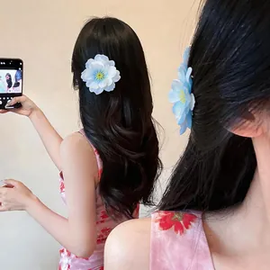 Detail of elegant large blue fabric flower hair claw clip styled on long wavy hair