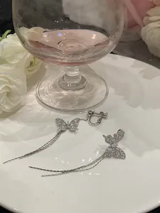 Detailed view of silver butterfly clip-on earrings with shimmering zirconia tassels.