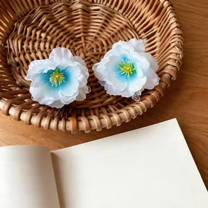 Detailed shot of two blue and white gradient fabric flower hair claw clips in a basket