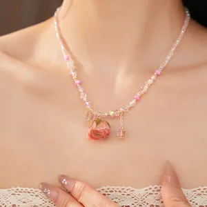 Detailed view showing the preserved rose pendant on a delicate pink glass bead necklace