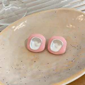 Détail de boucles d'oreilles géométriques roses avec un centre en émail blanc brillant