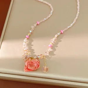 Detail view of a handmade glass bead necklace with a pink preserved rose pendant.