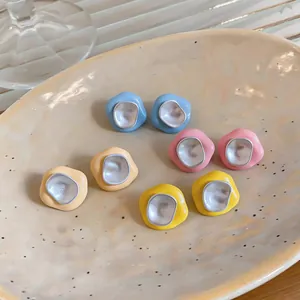 Gros plan sur des boucles d'oreilles géométriques minimalistes en émail coloré chic.