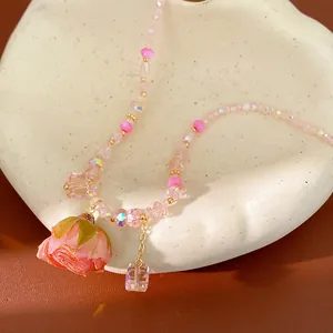 Detailed close-up of a pink beaded necklace featuring a preserved rose pendant on white