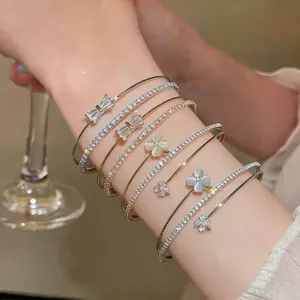 Primo piano di braccialetti di lusso francesi a strati con zirconi e ciondoli a quadrifoglio.
