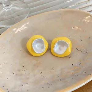 Gros plan de boucles d'oreilles géométriques en émail jaune et centre argenté