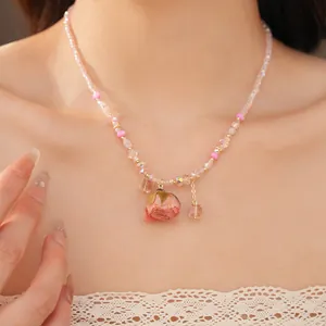 Close-up detail of a delicate pink beaded necklace with a real preserved rose pendant