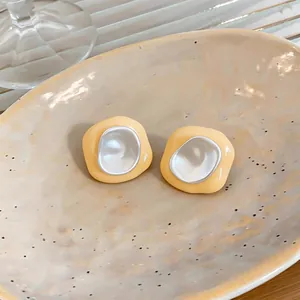Gros plan sur des boucles d'oreilles géométriques jaunes avec centre argenté brillant