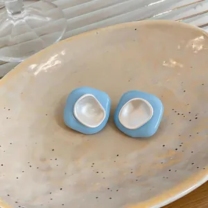 Gros plan de boucles d'oreilles géométriques en émail bleu ciel sur plateau en céramique