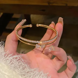 Primo piano di bracciale rigido a doppio strato con zirconi e fiocco dorato
