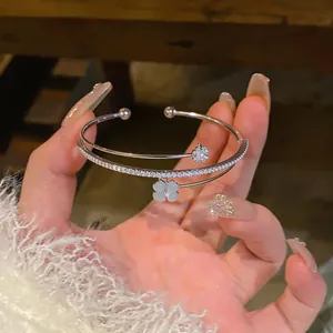 Primo piano di un bracciale rigido a doppio strato argentato con zirconi e quadrifoglio
